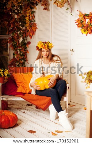 Beauty autumn woman smiling on the porch of yellow and orange autumn leaves. Stylish autumn girl