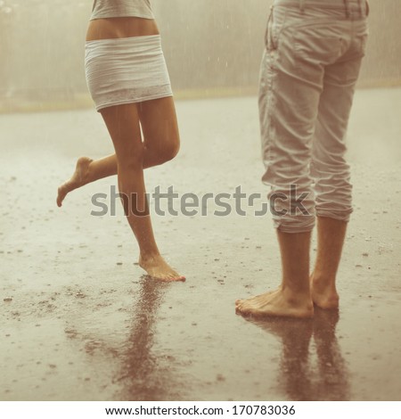 A loving young couple hugging and kissing under a rain. Two lovers, man and woman barefoot in the shower. Summer in love