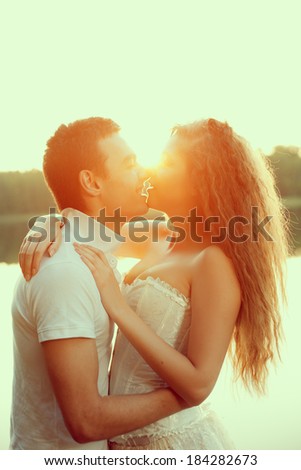 Loving couple hugging on the lake. Beautiful young woman and man in the background of the sun shining. Happy smiling Loves a date
