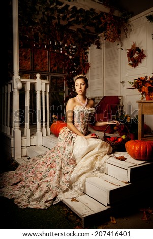 Young beautiful woman in vintage dress on autumn porch. Beauty girl in fall orange leaves