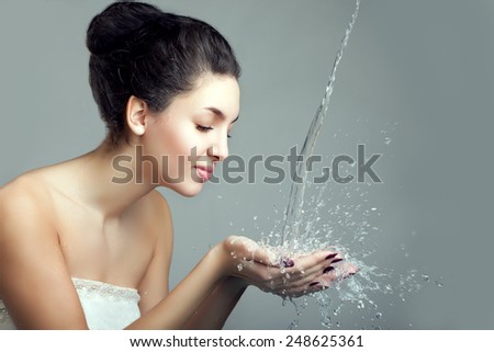 Woman and water splash. Water drops and bubbles in girls hands. Woman with young beauty face and water