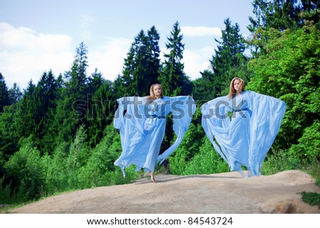 Two women, twins in the forest in a blue flowing dress