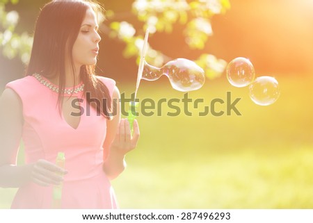 Young spring fashion woman blow bubbles Trendy girl in flowering trees in spring summer garden Springtime or summertime Lady in spring landscape background Allergic to pollen of flowers Spring allergy