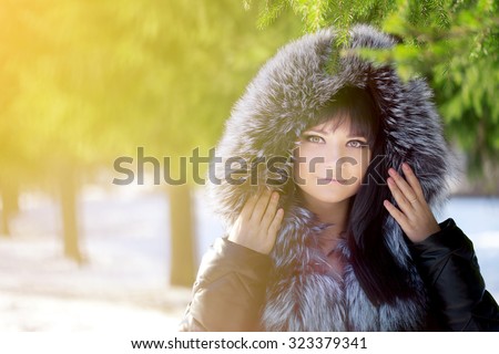 Winter woman on background of winter landscape sun. Fashion girl in forest wonderland. Winter sunset scene. Model in sunlight, backlight