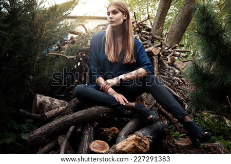 Fashion shooting outside at the forest vogue style woman sitting on the timbers