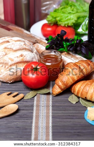 Fresh homemade bread and honey, vegetables on an old wooden table. Rustic style.