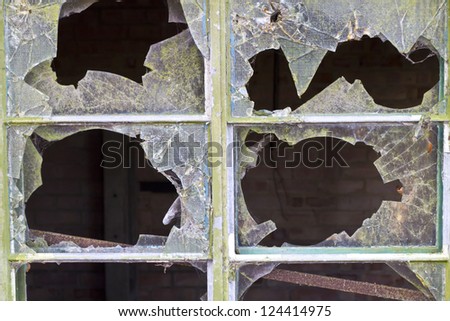Close up of smashed reinforced panes of glass in a window in a delapidated building