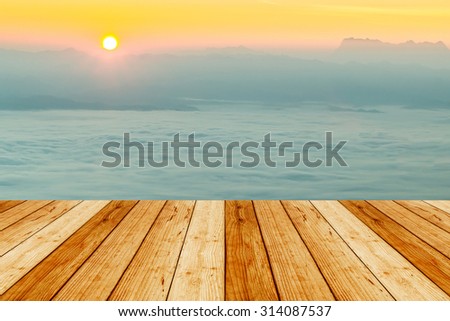 Empty wooden table with forest landscape with sun-rays thought fog.