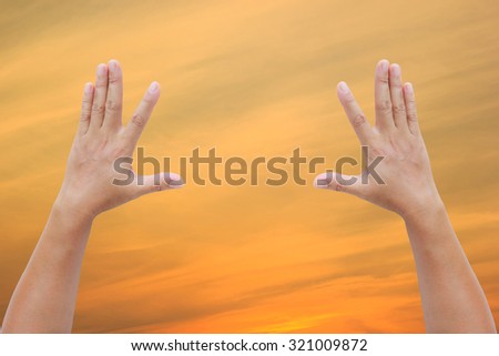 Asian female hand in sky gradient from blue to orange sunset