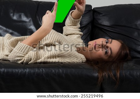 Happy young woman with tablet pc laying on sofa