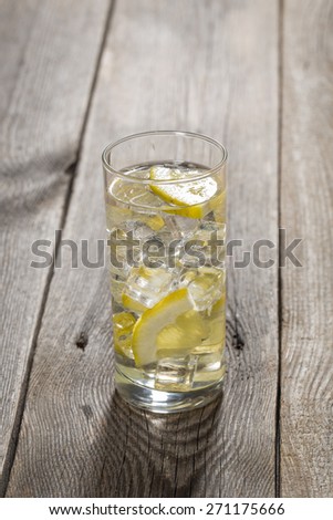 Lemon water with ice on wooden table.