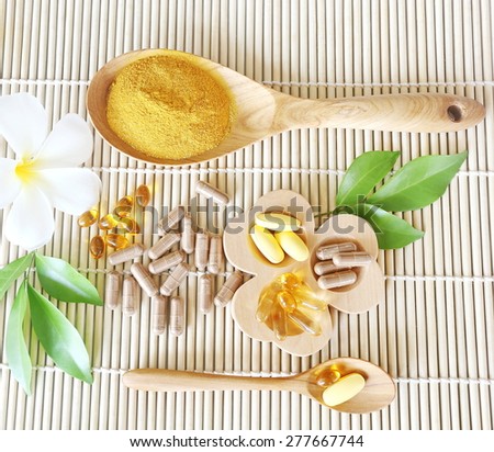 Herbal supplements and vitamins  on wooden trayand dry powder herbal inwooden spoon, decorated with white flowers and green leafsThe backdrop is the bamboo blinds