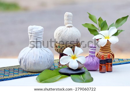 Thai traditional medicine. Body herbal ball, volatile oil, aromatherapy, pink yellow frangipani. The background is white cotton. Thailand blue striped drape the shawl
