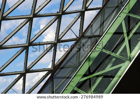 Tilt view of a transparent roof / dome as a sample of advanced contemporary architecture with extensive glazing. Escalator in green colors in a concept of green technologies, progress or growth.