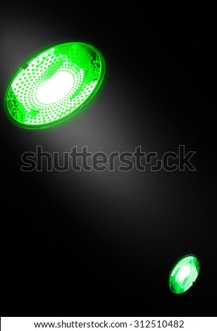 Collage of a couple of halogen electric lamps digitally turned green in concept of Green technologies, Energy efficiency or Energy saving. Ray of light on the dark wall can highlight a logo or text.
