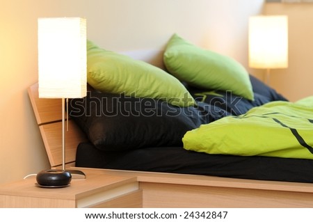 Two lamps in bedroom with green-black beddings