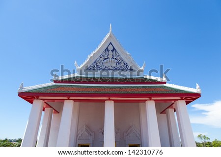 Large white temple. Many of the pillars. Behind the bright blue sky.