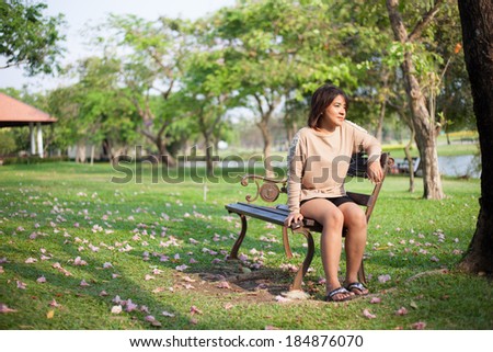 Woman sitting on bench Vacant look forward Blossoms in the Yard