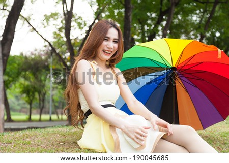 Woman sitting on the grass in the park. Posture relaxed and happy.