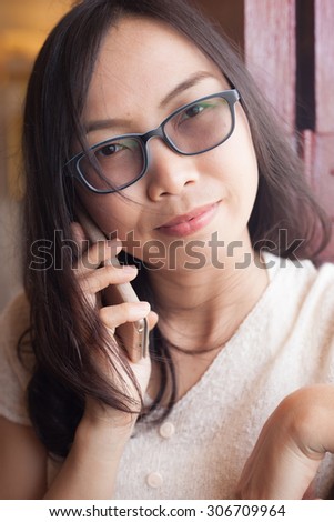 asia woman talk phoe.woman wear eyeglasses.woman braces and long black hair.