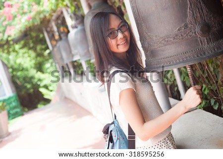 asia woman hit bell.joy and smile travel temple thailand.woman wear eyeglasses.