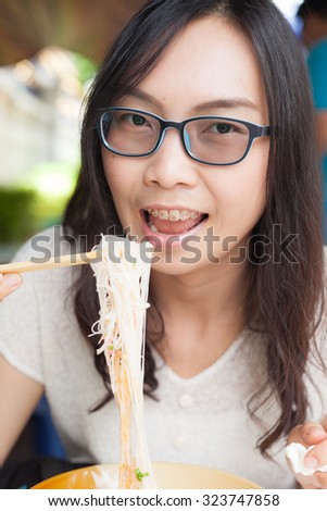 asia woman eat noodles.wear eyeglasses.joy and relax eat noodles.