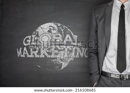 Global marketing concept on blackboard with businessman