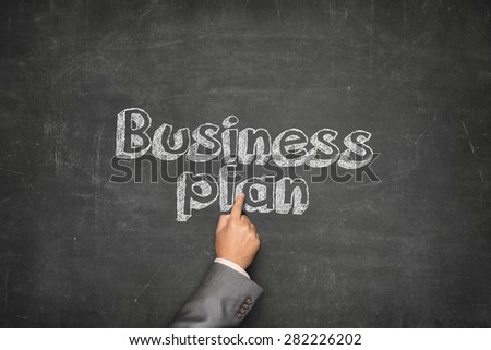 Business plan concept on black blackboard with businessman hand holding paper plane