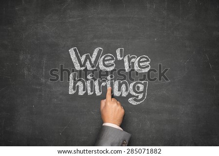 We are hiring concept on black blackboard with businessman hand