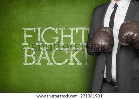 Fight back on blackboard with businessman on side wearing boxing gloves