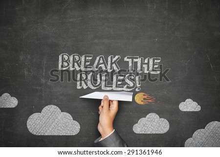 Break the rules concept on black blackboard with businessman hand holding paper plane