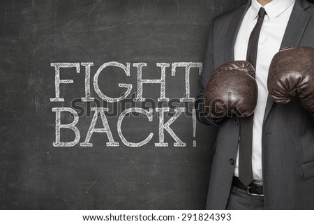 Fight back on blackboard with businessman on side wearing boxing gloves