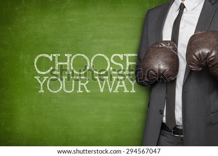 Choose your way on blackboard with businessman wearing boxing gloves