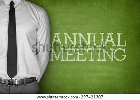 Annual meeting text on blackboard with businessman on side