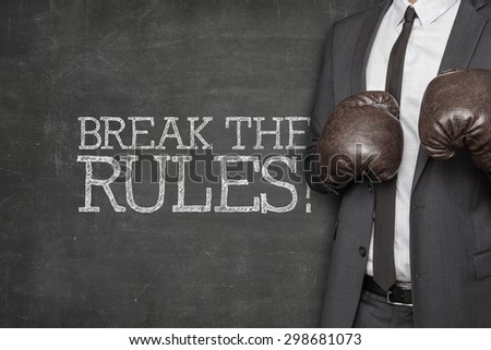 Break the rules on blackboard with businessman wearing boxing gloves