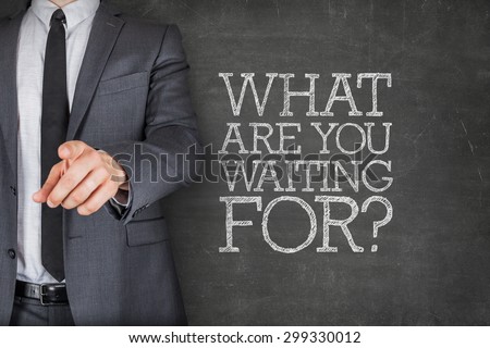 What are you waiting on on blackboard with businessman finger pointing