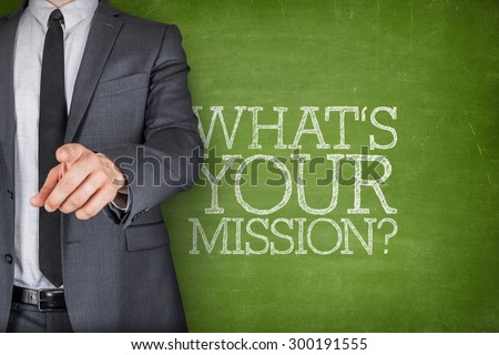 Whats your mission on blackboard with businessman finger pointing