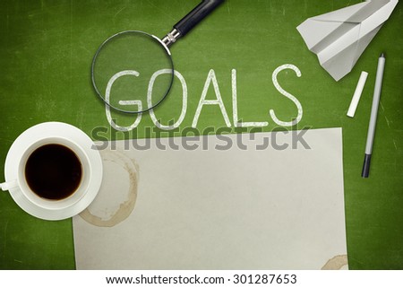 Goals concept on green blackboard with empty paper sheet and coffee cup