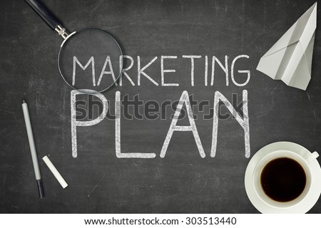 Marketing plan concept on black blackboard with coffee cupt and paper plane