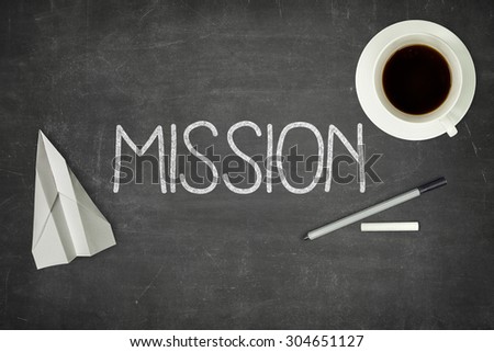 Mission concept on black blackboard with coffee cup and paper plane