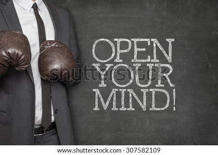 Open your mind on blackboard with businessman wearing boxing gloves