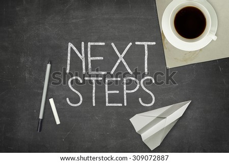 Next step concept on black blackboard with coffee cup and paper plane