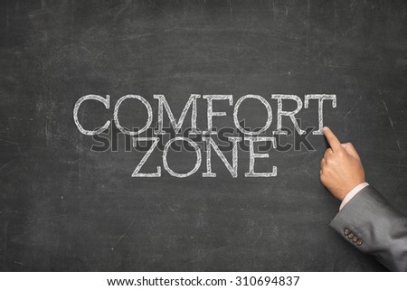 Comfort zone text on blackboard with businessman hand pointing