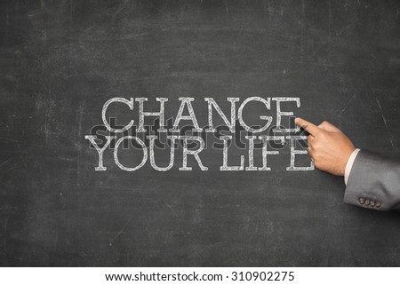 Change your life text on blackboard with businessman hand pointing