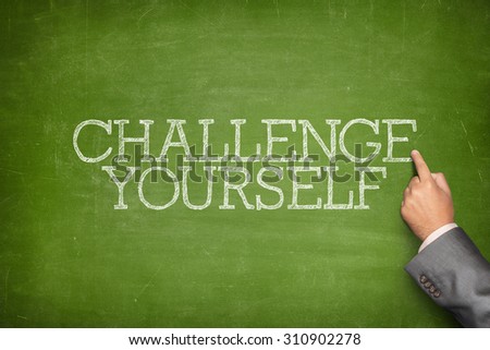 Challenge yourself text on blackboard with businessman hand pointing