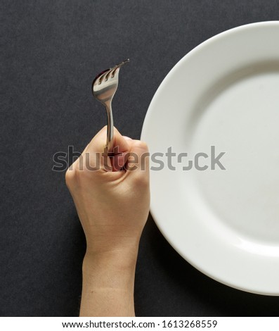 Fork and knife in hands on black background with white plate. Сток-фото © 