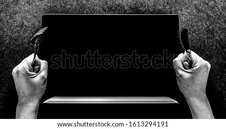 Fork and knife in hands on black background with black rectangular plate. Сток-фото © 