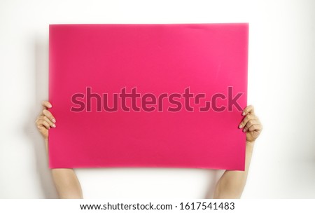 Photo of A large sheet of red paper in hands on a white background. Copy space. Woman hold blank card. 
