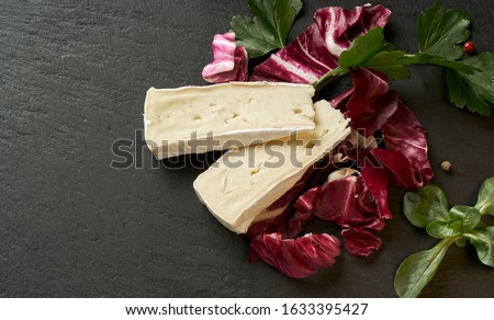 Delicious brie cheese with lavender on black background. Brie type of cheese. Camembert. Fresh Brie cheese and a slice on stone board. Italian, French cheese Сток-фото © 