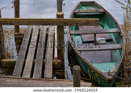 A small green boat floating on the lake near the pier. Foto d'archivio © 